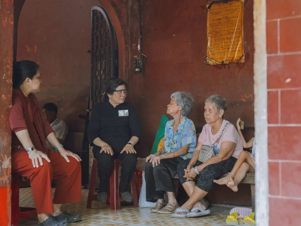A candid scene of elderly women engaging in conversation inside a rustic room, fostering community spirit.
